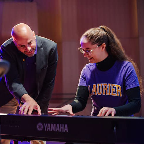 A professor coaching a student playing keyboard
